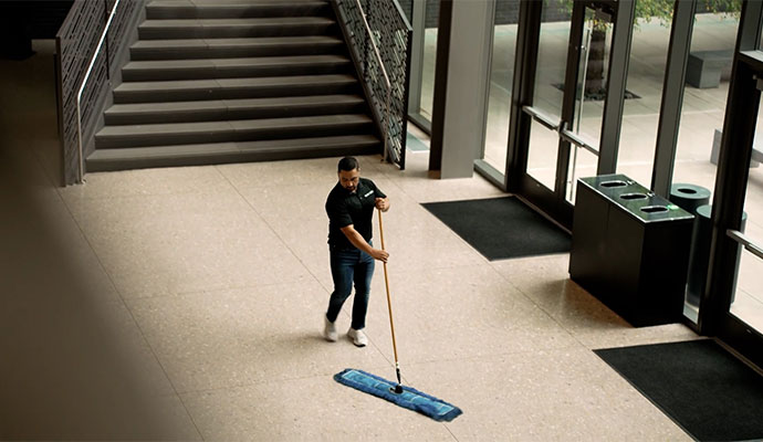 A Professional cleaning commercial floor using a dust mop